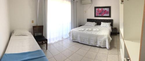 a bedroom with a bed and a large window at Vila Alaide Praia Hotel in Barra Velha