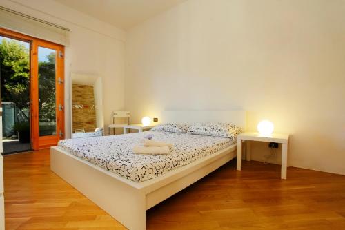 a white bedroom with a bed and two lamps at Ombelico di Venere House in Altavilla Milicia