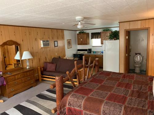 Phillips Historic Motel & Cottages في روبينسفيل: غرفة نوم بسرير ومطبخ مع أريكة