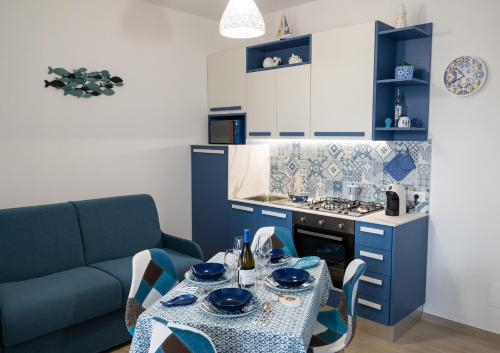 a blue kitchen with a table and a couch at MARE e Terra Holiday fronte mare in San Vito lo Capo