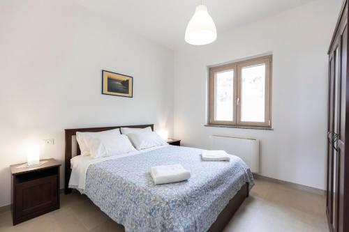 ein weißes Schlafzimmer mit einem Bett und einem Fenster in der Unterkunft Villa Alice in Capo Vaticano