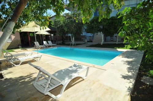 een zwembad met een stoel, een tafel en een avisorvisor bij Likya Apart Hotel in Kemer