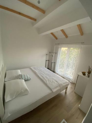 a bedroom with a large white bed with a window at Ravne Rest House in Visoko