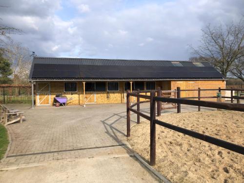 a barn with a building with a black roof at Horse and Hound in Riethoven