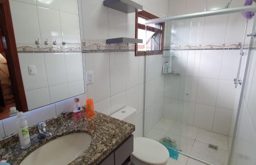 a bathroom with a sink and a toilet and a shower at Apto Centro de Gramado com Praticidade e Conforto in Gramado