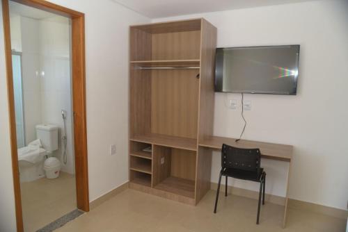 Zimmer mit einem Schreibtisch, einem TV und einem Stuhl in der Unterkunft Boa Esperança Apart Hotel in Boa Esperança