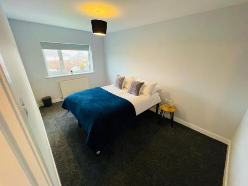 a bedroom with a bed with a blue blanket and a window at Newly refurbished 3 bedroom house in Heysham