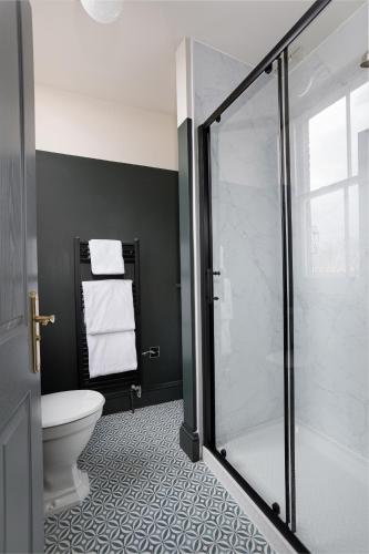 a bathroom with a toilet and a glass shower at Swan & Railway Hotel Wigan in Wigan