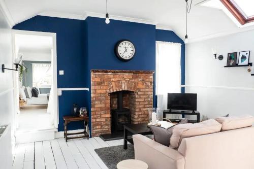a living room with a clock on a blue wall at Cute Self Catering Flat in the Brecon Beacons in Crickhowell
