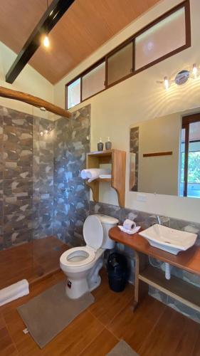 a bathroom with a toilet and a sink and a shower at Cabañas Armonía y Jardín de Orquídeas in Mindo
