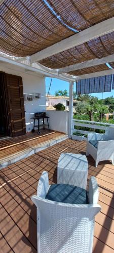 a patio with white chairs and a table at Appartamentino in villa a 2 passi dal mare in Fontane Bianche