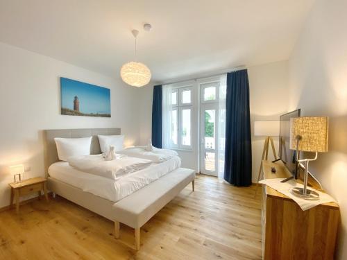 a bedroom with a large white bed and a television at Villa Jenny Sassnitz Villa Jenny - Appartement 3 in Sassnitz