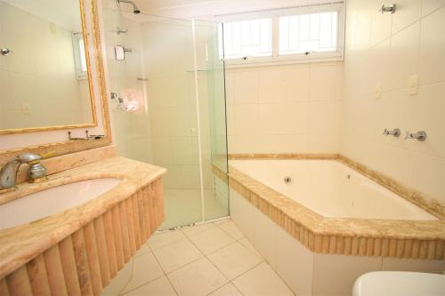 uma casa de banho com uma banheira, um lavatório e um chuveiro em Casa Beira Mar em Bombinhas