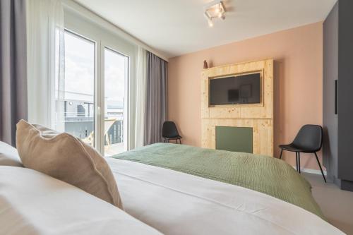 a bedroom with a large bed with a television on the wall at Arbio Hotel Freiburg in Freiburg im Breisgau