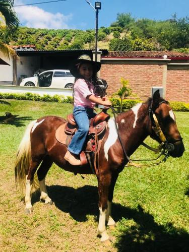a little girl is sitting on a horse at Hotel Campestre La María Toro Valle in Toro