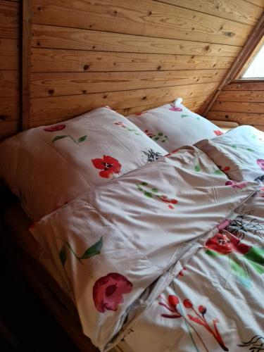 an unmade bed with red flowers on it at Leśna Chatka in Wola Polska