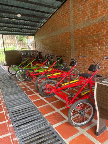 a row of red and green bikes parked next to a brick wall at Hotel Campestre La María Toro Valle in Toro