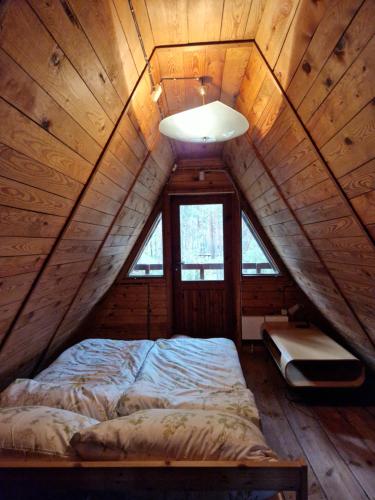 a bed in a room with a ceiling with a window at Leśna Chatka in Wola Polska