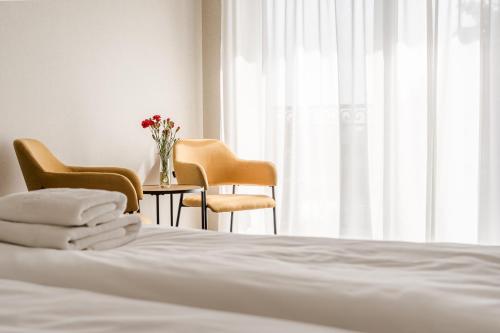 a bed with two chairs and a table with a vase of flowers at Villa Verdi Pleasure & Spa in Łeba