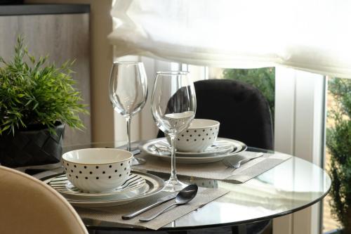 a glass table with two wine glasses and dishes on it at El Balconcillo - Apartamento boutique en pleno centro - Grupo Querbes in Gijón