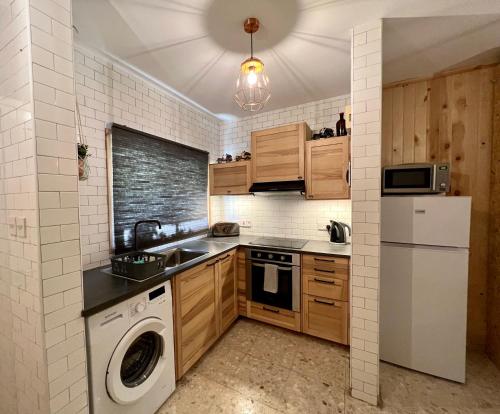 a kitchen with wooden cabinets and a washer and dryer at FatCow Beach House 43 in Larnaka