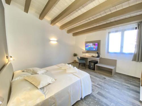 1 dormitorio con 1 cama blanca grande y escritorio en L'Ulivo Comfort Rooms, en Terrasini