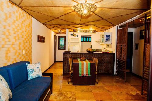 a living room with a blue couch and a kitchen at Pousada Village Porto Mirim por Carpediem in Jacumã