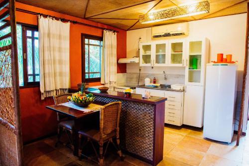a kitchen with a table and a refrigerator at Pousada Village Porto Mirim por Carpediem in Jacumã