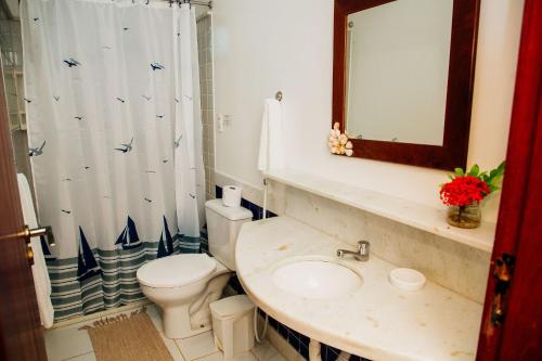 a bathroom with a toilet and a sink and a mirror at Pousada Village Porto Mirim por Carpediem in Jacumã
