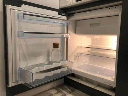 an empty refrigerator with a bottle sitting inside of it at 2 Bedroom Garden Studio in Cambridge City Centre with Parking in Cambridge