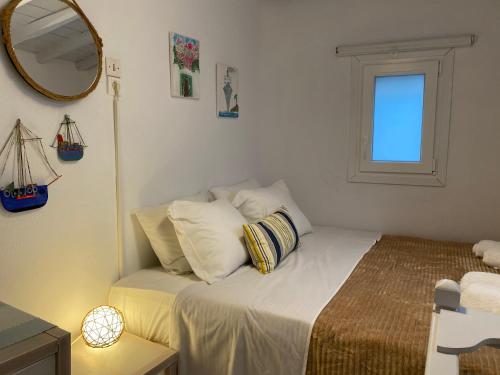 Un dormitorio con una cama con almohadas y un espejo. en BUDGET DOWNTOWN APARTMENT- Harma I, en Mykonos ciudad