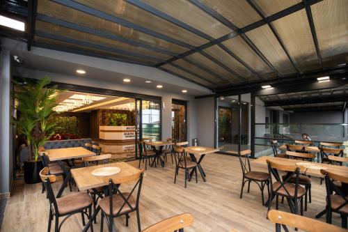 Marina Green Suite & Residence في طرابزون: مطعم بطاولات وكراسي خشبية ونوافذ