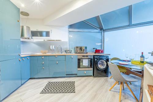 a kitchen with blue cabinets and a table and a stove at Suite "comme à Venise" vue sur Metz Opéra avec parking inclus in Metz