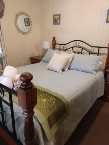a bedroom with a bed with a wooden frame at Amiens Cottage, historic, quiet, in heart of Stanthorpe in Stanthorpe