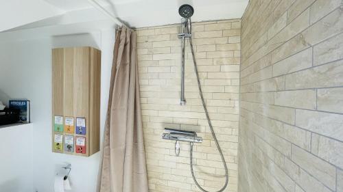 a shower in a bathroom with a stone wall at ApartmentInCopenhagen Apartment 1490 in Copenhagen
