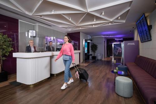 une femme avec une valise traversant un bar dans l'établissement YOTELAIR Istanbul Airport, Duty free - International Transit area, à Istanbul