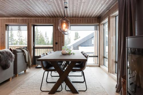 comedor con mesa, sillas y ventanas en Cozy modern holiday villa with electric car charging, sauna and fireplace en Øyer