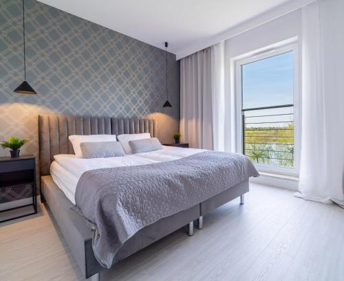 a bedroom with a large bed and a large window at Bella Vista Apartment in Iława