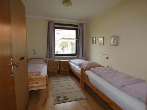 dwa łóżka w pokoju z oknem w obiekcie To Hus, Whg 2 w mieście Kellenhusen