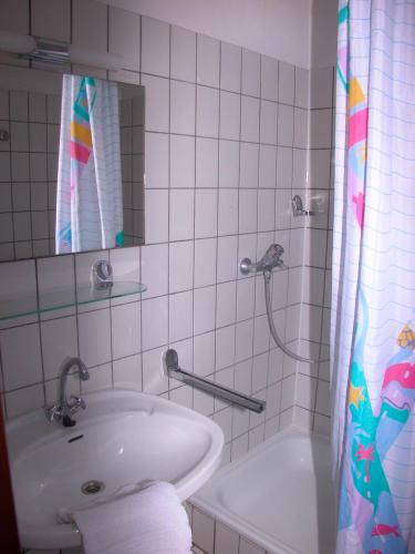 La salle de bains blanche est pourvue d'un lavabo et d'une douche. dans l'établissement Silva Mare, UG 2, à Kellenhusen
