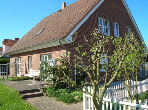 een rood bakstenen huis met een wit hek ervoor bij Haus Jodokus, Whg Professor Paljass in Kellenhusen