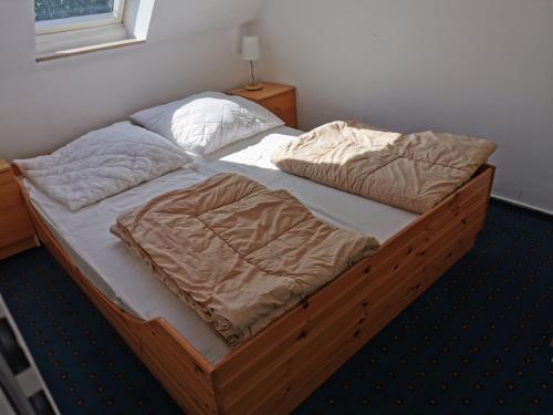 a bed with a wooden frame with two pillows at Rosa Canina W11 in Kellenhusen