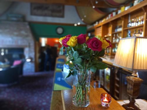 un vaso di fiori seduto su un tavolo con una lampada di Golden Ball Hotel a Cambridge