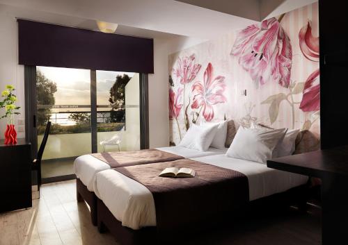 sypialnia z dużym łóżkiem i dużym oknem w obiekcie Airotel Patras Smart Hotel w mieście Patras
