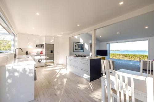 a kitchen with white cabinets and a large window at Driftwood Beach House with Spa Pool - Absolute Beachfront! in Blackpool