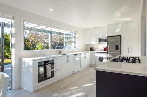 a kitchen with white cabinets and a large window at Driftwood Beach House with Spa Pool - Absolute Beachfront! in Blackpool