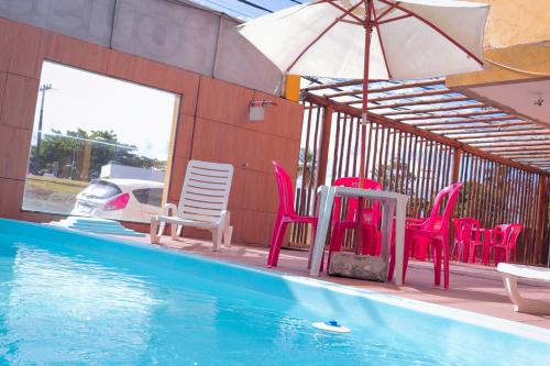 a group of chairs and an umbrella next to a swimming pool at Pousada e Restaurante Palomar in Ilhéus