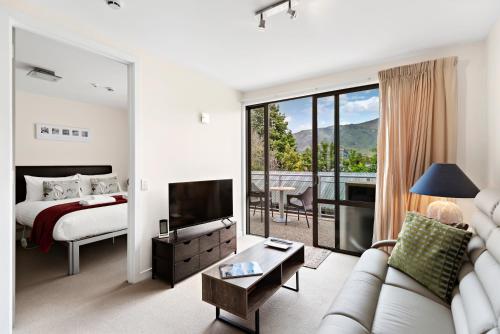 een slaapkamer met een bed en een woonkamer met een bank bij Belvedere Apartments in Wanaka