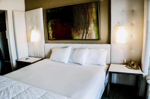 a bedroom with a bed with white sheets and pillows at Devonshire Inn Motel in Rosamond