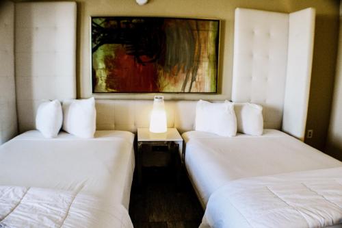 a room with two beds and a painting on the wall at Devonshire Inn Motel in Rosamond